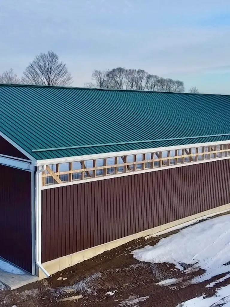 Completed barn restoration project with fresh siding and metal roof in rural Ontario