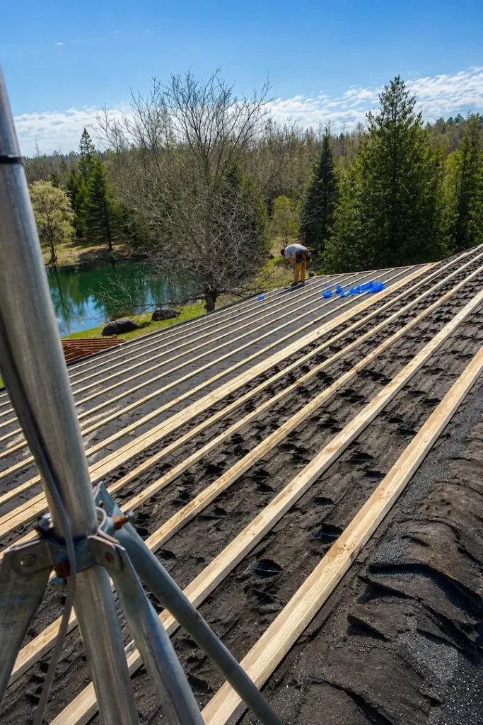 Custom-bent metal trim being fitted at roof ridge detail on Pontypool steel roof installation