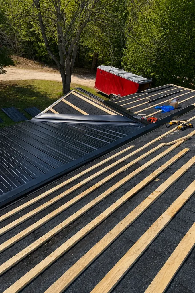 Spruce strapping installed horizontally over existing asphalt shingles before steel panel install